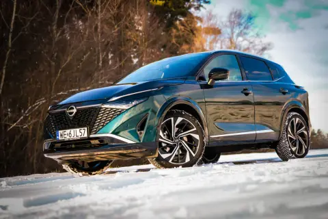 Zielony Nissan Qashqai Tekna na śniegu. Bogate wyposażenie tego SUV-a w zimowej scenerii.