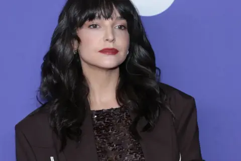Maria Dębska, z partnerem u boku, prezentuje się elegancko w ciemnej marynarce i błyszczącej bluzce.