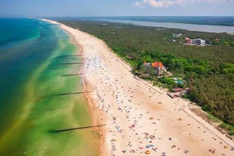 Widok z lotu ptaka na plażę w Łebie z turystami, morzem i lasem.