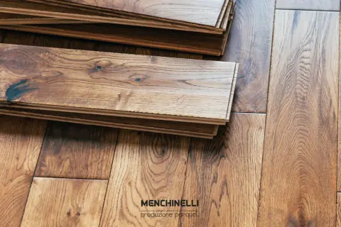 Tavole di parquet in legno grezzo, pronte per il trattamento. La venatura del legno è ben visibile, con nodi scuri che aggiungono carattere.