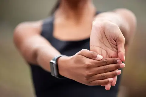 Une personne étire son poignet, peut-être pour soulager une douleur tendon poignet après un effort.