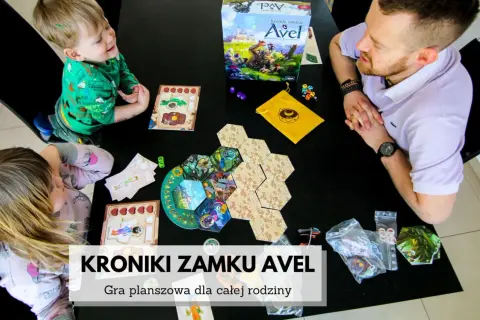 Rodzina gra w "Kroniki zamku Avel". Plansza i elementy gry rozłożone na czarnym stole, dzieci i dorosły skupieni na rozgrywce.