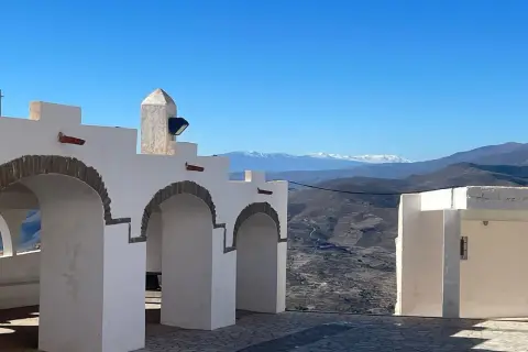 Arcos blancos y un paisaje montañoso nevado en la sierra de Almería bajo un cielo azul.