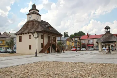Rynek w Pilicy z ratuszem i studnią. Urokliwe miasto z brukowanym placem i kolorowymi kamienicami.