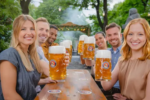 Freunde stoßen mit großen Krügen unfiltriertes Bier an.