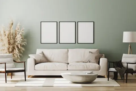 Miętowa ściana idealnie komponuje się z białymi meblami, tworząc przytulną aranżację. Sofa, fotele i stolik kawowy w jasnych barwach.
