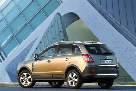 Złoty Opel Antara z nowoczesnym budynkiem w tle.