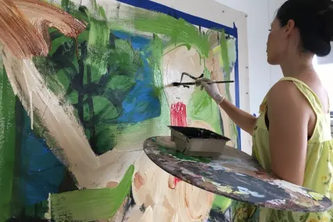 Lucy Liu artwork in progress: the artist adds bold strokes of black paint to a vibrant, abstract canvas, her palette ready for more color.