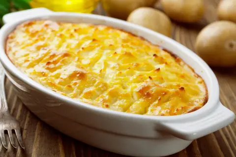 Herzhaftes Kartoffelgratin mit gekochten Kartoffeln, goldbraun überbacken in einer weißen Auflaufform.