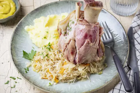 Deftig zubereitetes Eisbein in Sauerkraut kochen, serviert mit Kartoffelpüree und Senf.