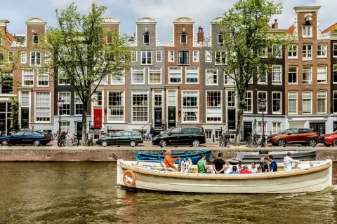 En båttur på kanalerna är ett måste i Amsterdam. Vackra hus och träd kantar vattnet.