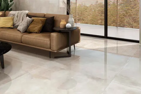 Elegante salón con sofá de cuero y suelo de gran formato, ideal para colocar baldosas.
