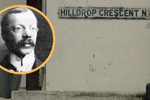 Czarno-białe zdjęcie mężczyzny w okularach i wąsach obok tabliczki z napisem "HILLDROP CRESCENT.N.".