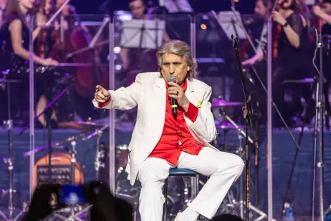 Toto Cutugno, w białej marynarce i czerwonej koszuli, śpiewa "L'Italiano".