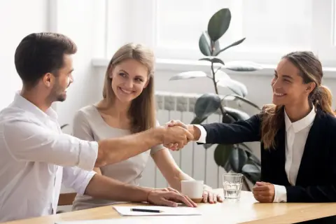 Accordo raggiunto: stretta di mano tra uomo e donna, con una collega sorridente. Si discute di stage e retribuzione minima.