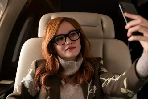 Anna Delvey, grana przez Julię Garner, w luksusowym wnętrzu samolotu, robiąc selfie.