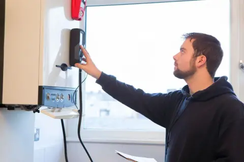 Un technicien vérifie une chaudière, s'assurant que la tuyauterie gaz respecte la réglementation.