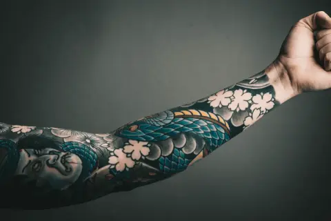 Rękaw z tatuażem yakuza: wąż oplatający twarz i kwiaty wiśni.