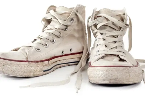 Zwei abgetragene, weiße Chucks mit Schnürsenkeln, bereit zum Chucks waschen.