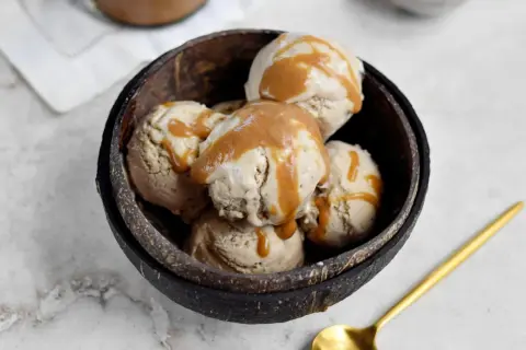 Schüssel mit erdnussbutter eis, beträufelt mit Karamellsauce. Ein goldener Löffel liegt daneben.