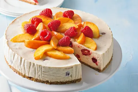 Cremiger Pfirsich Melba Kuchen mit frischen Himbeeren und Pfirsichspalten, ein Genuss für Augen und Gaumen.