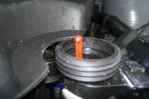 Zbiorniczek płynu chłodniczego w BMW E46. Pomarańczowa miarka wskazuje poziom płynu.