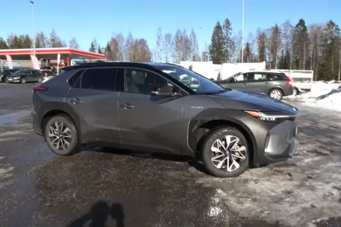 Szary Toyota bz4x test na tle stacji benzynowej i zaśnieżonego terenu.