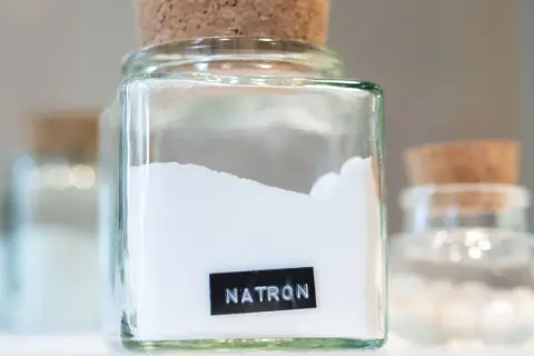 Glasbehälter mit Natron, bereit zum Putzen. Ein weiteres Glas mit Natron steht im Hintergrund.