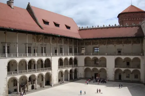 Dziedziniec zamku królewskiego na Wawelu, z arkadowymi krużgankami i wieżą. Ciekawostki o historii tego miejsca czekają na odkrycie.