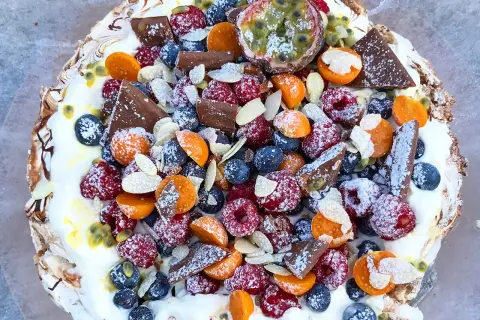 En härlig pavlova tårta fylld med färska bär, passionsfrukt, choklad och mandel.