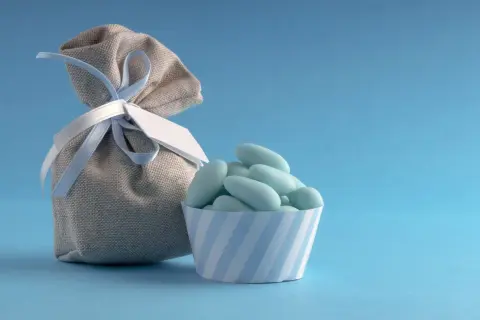 Un sachet de dragées bleues, parfait pour un thème baptême garçon, avec une petite coupelle rayée.
