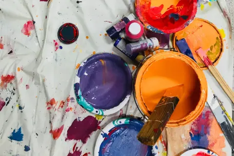 Pots de peinture acrylique ouverts, éclaboussés sur une toile. La durée conservation peinture acrylique dépend de son stockage.