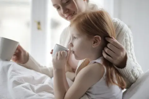 Ciepły uścisk mamy, gdy dziecko z autyzmem pije z kubeczka.