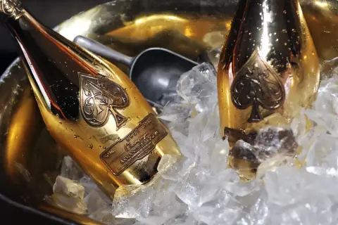 Dwie złote butelki szampana Armand de Brignac w wiaderku z lodem. To szampan drogi, symbol luksusu i celebracji.