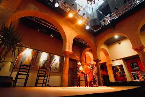 Escenario listo para la gracia flamenca. Sillas, guitarras y cuadros evocan la pasión del arte.