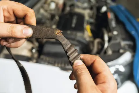 Zużyty pasek rozrządu Toyoty Aygo w rękach mechanika.