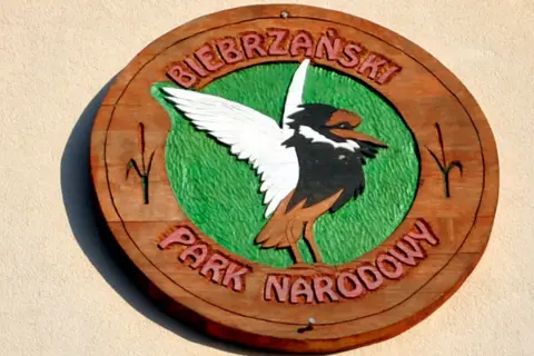 Drewniany symbol Biebrzańskiego Parku Narodowego z ptakiem i napisem.