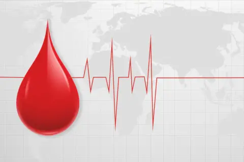 Kropla krwi na tle mapy świata i wykresu EKG. Symbolizuje życie i zdrowie, a także podkreśla, jak cenna jest najrzadsza grupa krwi.