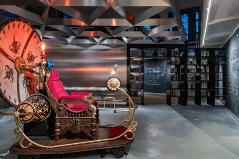 Máquina del tiempo inspirada en H. G. Wells, con asiento de terciopelo rojo y detalles dorados, lista para viajar.