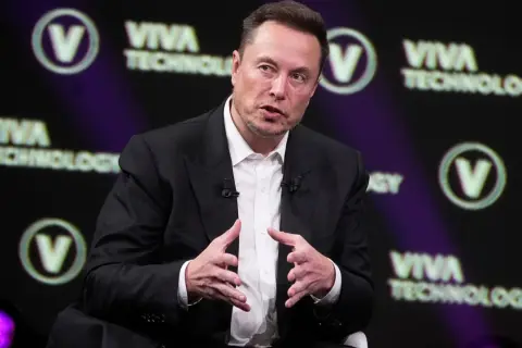 Elon Musk w garniturze, przemawiający na tle logo Viva Technology.