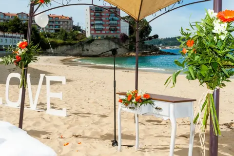 Decoración de boda en la playa de lagos Bueu: letras "LOVE", mesa de altar, flores y el mar azul.