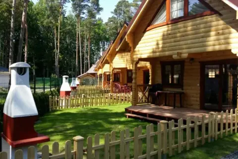 Nawrapark Pobierowo domki letniskowe: drewniane domki z tarasami i grillami, otoczone zielenią i lasem.