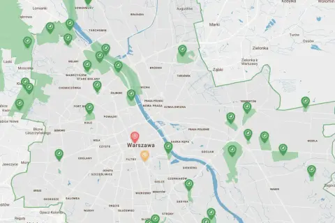 Mapa zielonych terenów i ścieżek rowerowych w okolicach Warszawy. Widać zaznaczone obszary zielone i punkty z ikonami rowerów.