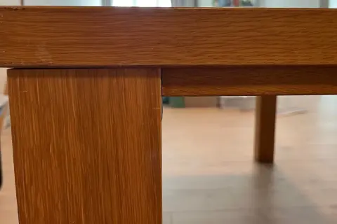 Detaljbild av ett träbord i fanér, redo för renovering.