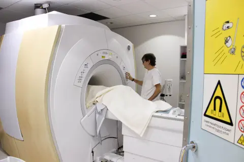 Un technicien prépare un patient pour une IRM. La question "combien d'IRM peut-on faire par an" dépend de la prescription médicale.