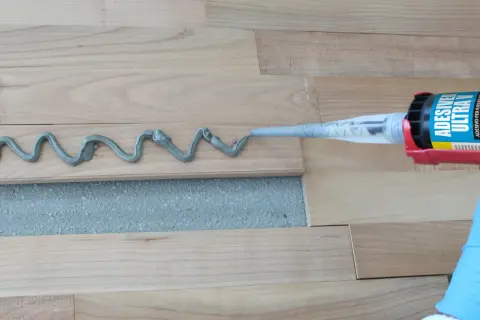 Aplicando adhesivo para parquet con pistola. Preparando para barnizar parquet.