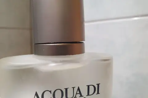 Szklana butelka z napisem ACQUA DI GIO 100ml, z metalową nakrętką.
