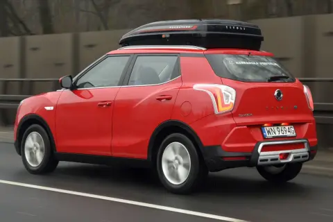 Czerwony SsangYong Tivoli z boxem dachowym, gotowy na podróż. Wiele pozytywnych ssangyong tivoli opinie potwierdza jego wszechstronność.