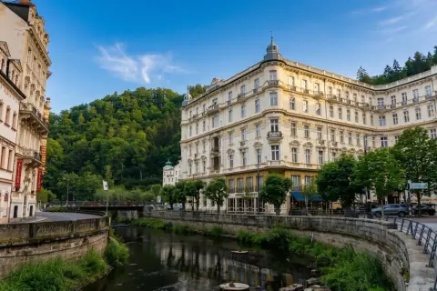 Eleganckie budynki w Karlowych Warach nad rzeką, otoczone zielenią. Urokliwe karlowe wary termy zachęcają do relaksu.