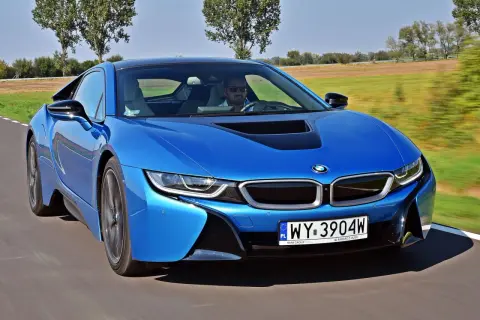 Niebieskie BMW i8 w ruchu. Kierowca w okularach przeciwsłonecznych. Sprawdź aktualną bmw i8 cena.